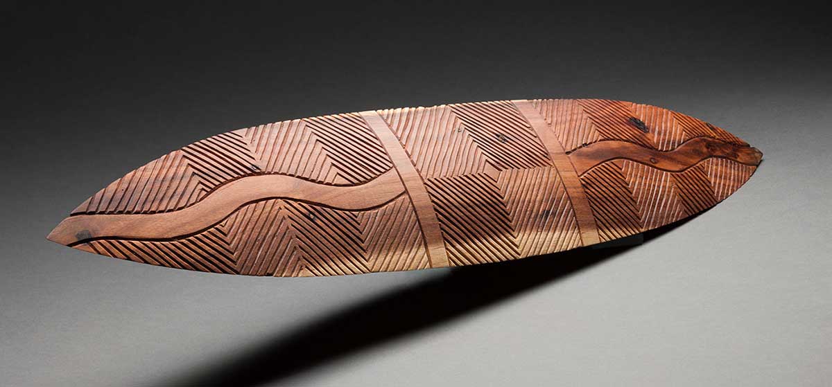 A carved wooden shield featuring various geometric patterns and motifs.