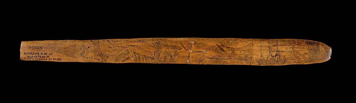 Wooden message stick engraved with motifs and handwritten text on one end reading ‘EXTREME N.W. OF W. AUSTRALIA’.