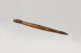 Flute putorino Flute made of wood with two halves mounted together. A carving at the lower closed end and the upper open end is a human head with mother-of-pearl eyes and an extended tongue.