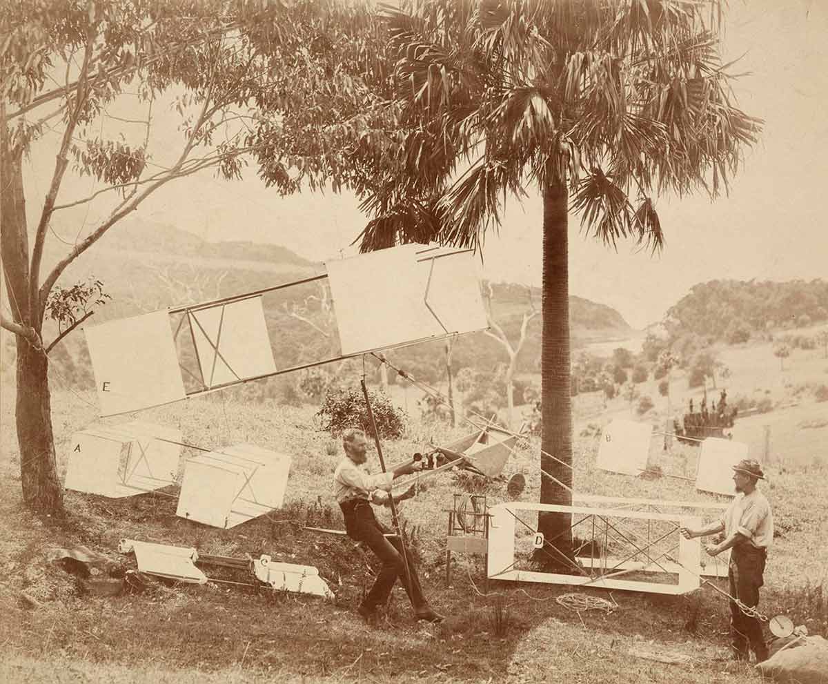 Black and white photograph of two men with a series of kites
