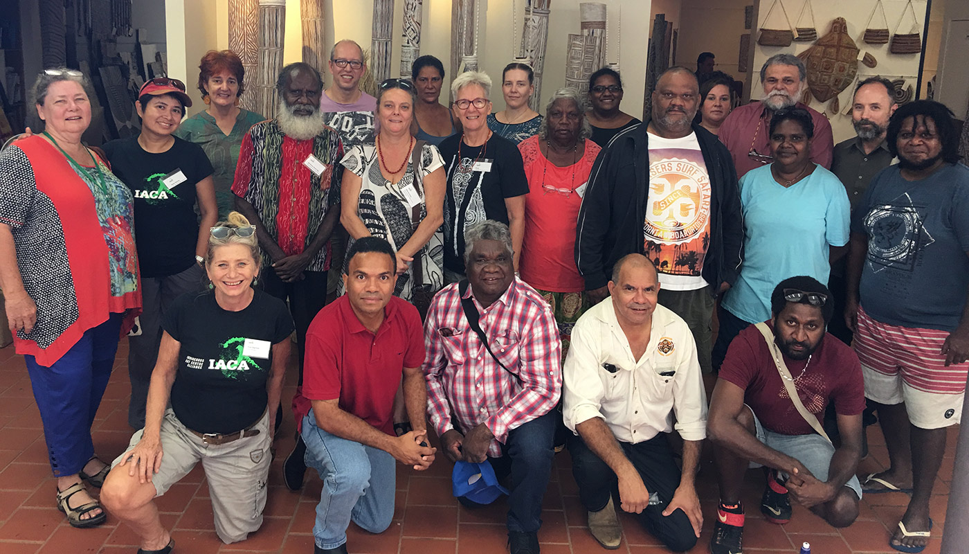 A group photo of several people with Indigenous artworks in the background.
