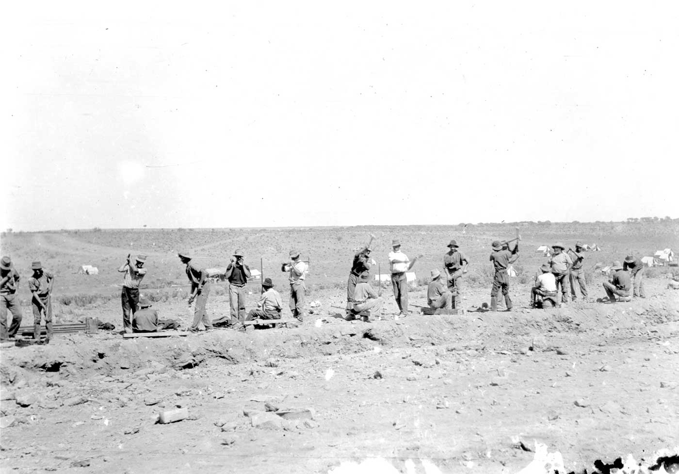 A black and white photo of railway construction workers in the desert.