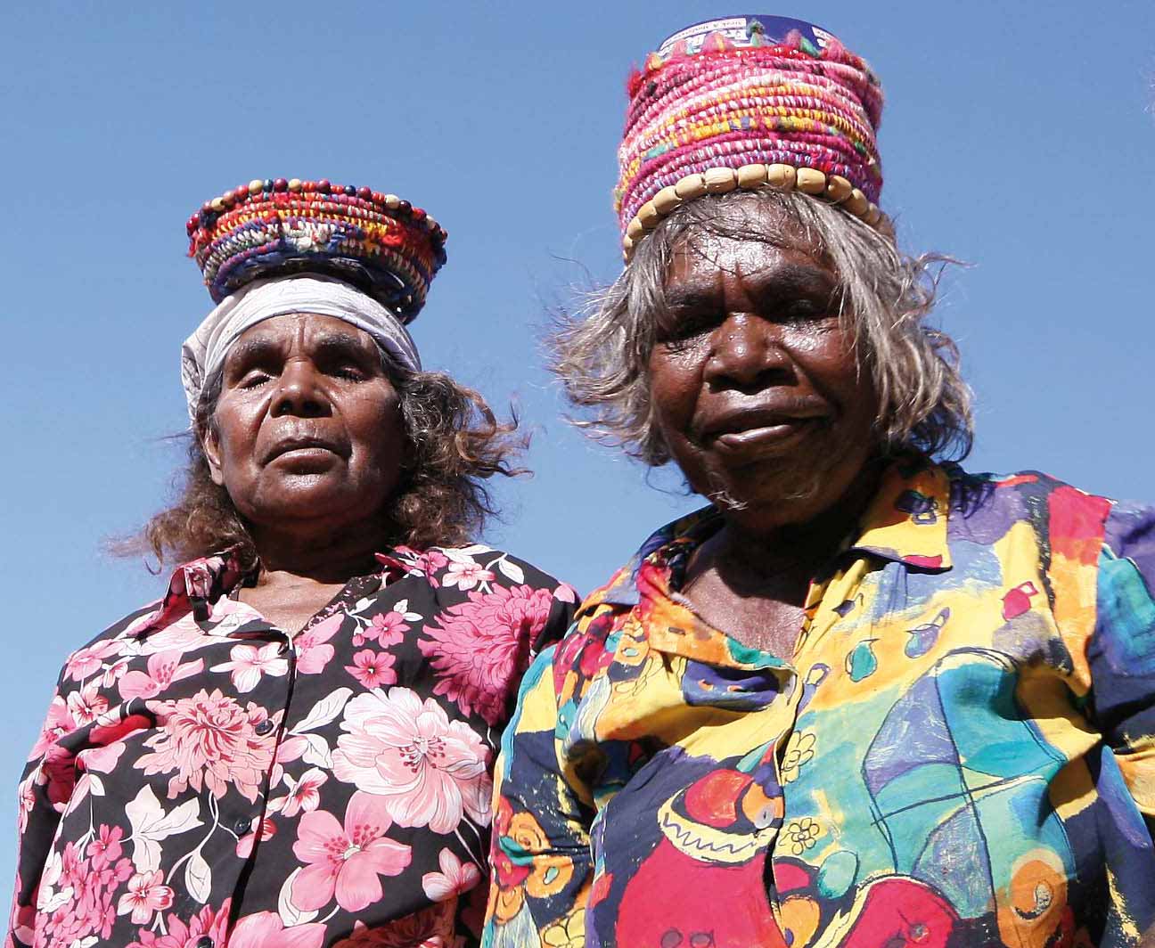 Colour photograph of two women with colourful woven baskets on their heads.