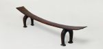Headrest kali Headrest made of wood, the ‘seat’ is slightly curved and supported by a pair of horseshoe-shaped legs. The ‘seat’ becomes wider from the middle towards both ends.