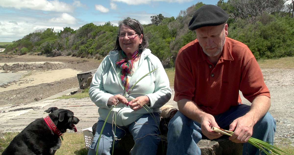 A man, a woman and a dog on a beach.