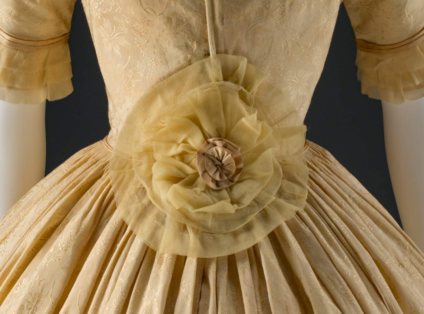 A large gold silk chiffon and satin rosette at the back of the dress conceals alterations to enlarge the waistline.