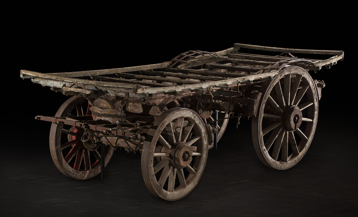 A flatbed wagonmade of timber, with larger wheels at the rear.
