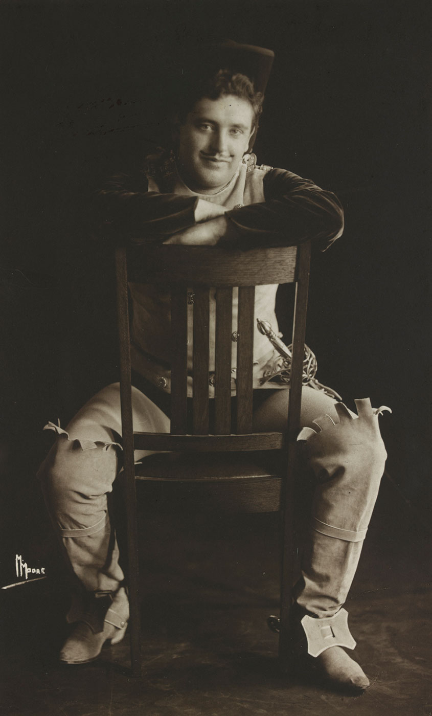 Studio portrat of John McCormack sitting astride a chair.