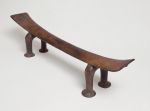 Headrest kali Headrest made of wood, the ‘seat’ is slightly curved and supported by a pair of horseshoe-shaped legs. The ‘seat’ becomes wider from the middle towards both ends.