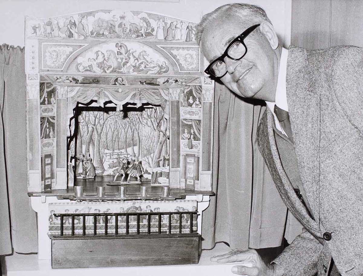A man poses in front of model of a theatre.