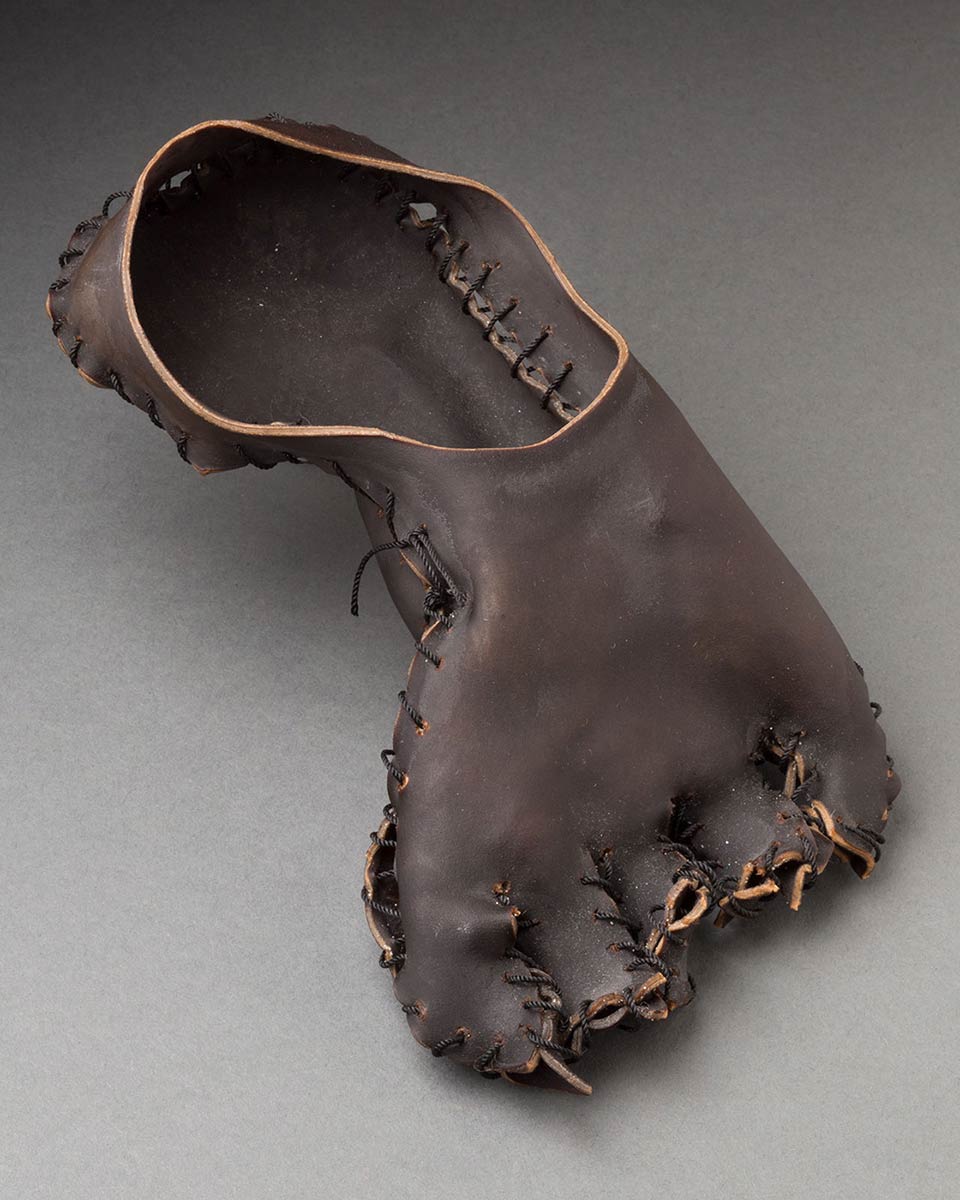 Lengths of dark brown, bull sea kelp, sewn together with black nylon string to form a sculpture of a foot.