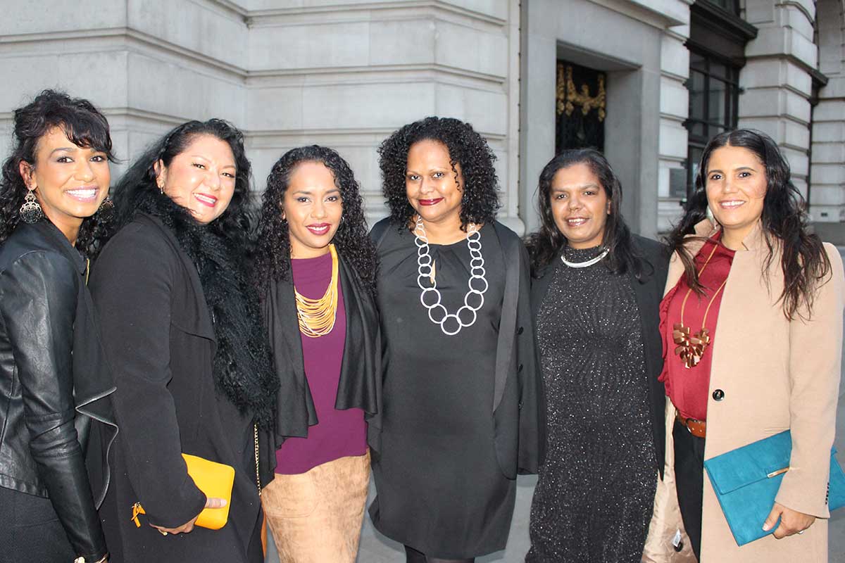 Six women pose for the camera outside a building.