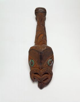 Architectural ornament A canoe ornament made of wood and coloured red. The carving features a human face with tongue extended and the larger face with inlaid mother-of -pearl eyes.
