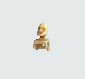 Hat ornament Hat ornament made of the bone of a marine animal, carved into the form of a seated male figure, with eye sockets large and deep, and mouth slightly open.