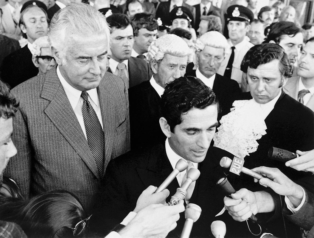 Gough Whitlam surrounded by a crowd of people as David Smith addresses the media.
