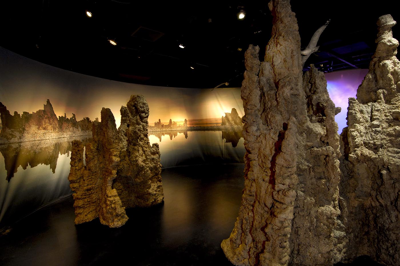 Brown-coloured mineral formations rise in front of panels depicting a lakeside scene.