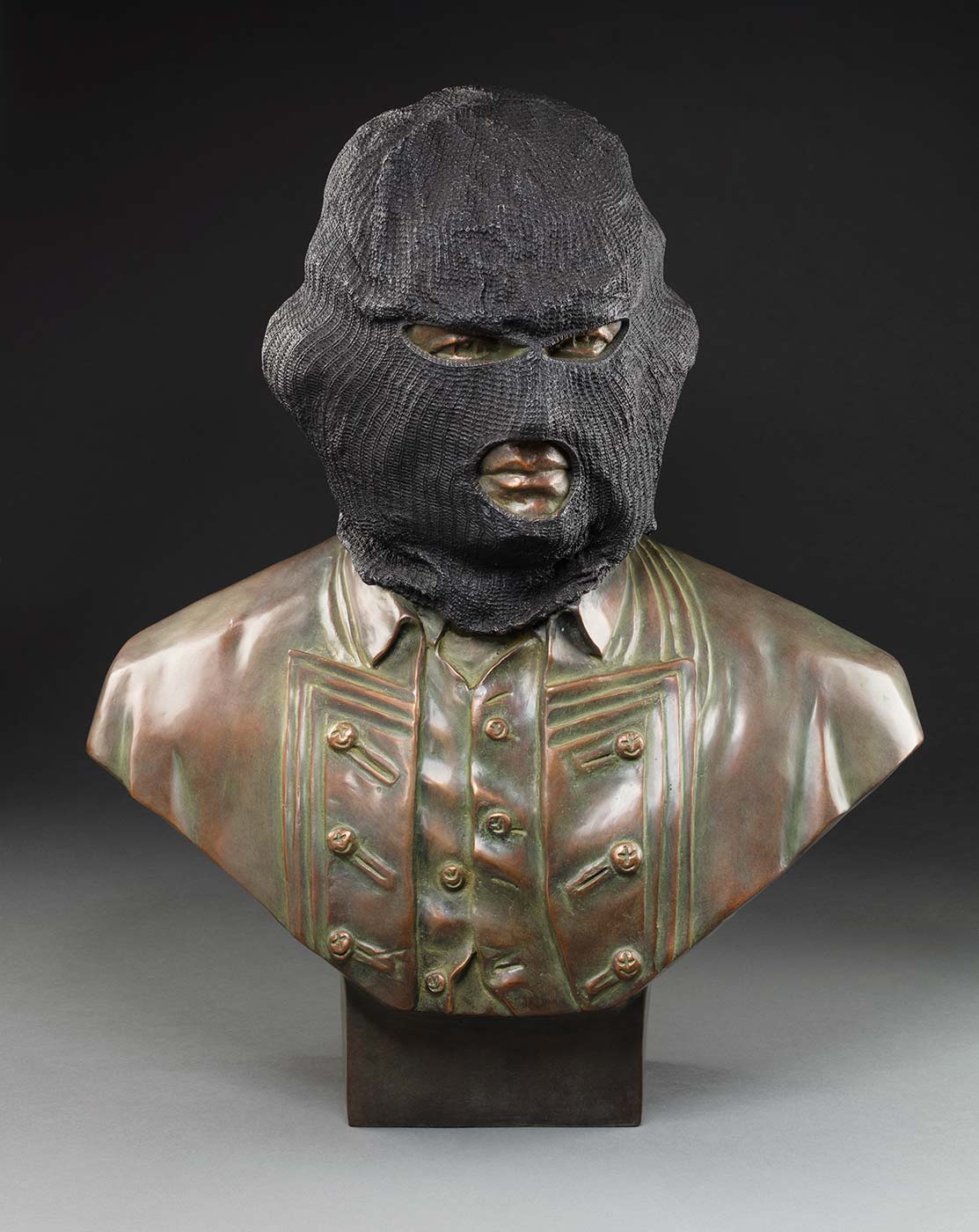 A bronze bust of a males head with a ponytail wearing a dark grey Balaklava.