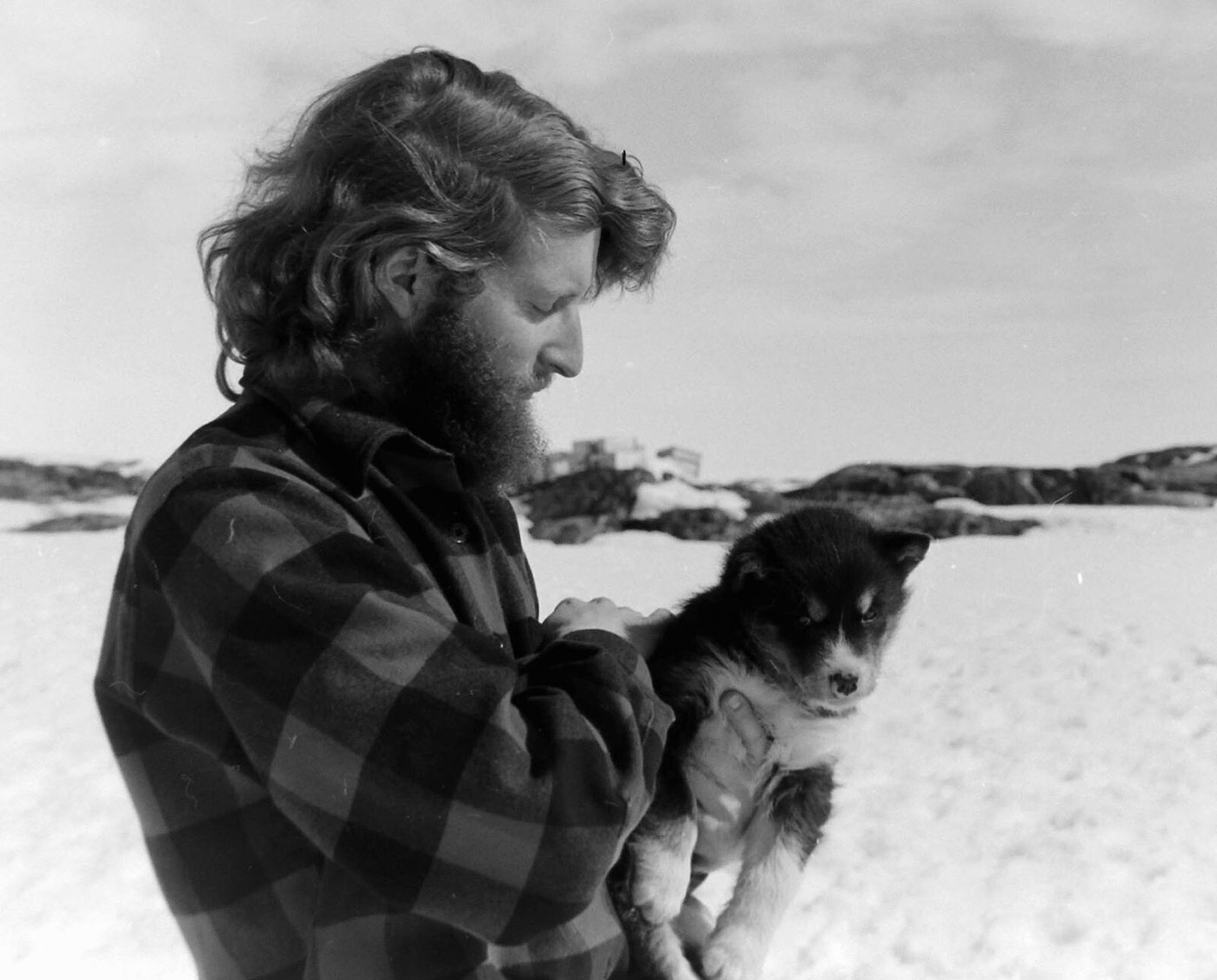 Black and white photograph of a man holding a husky pup.