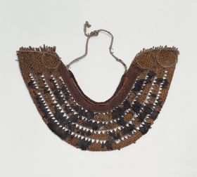 Breast ornament (gorget) taumi Horseshoe-shaped, collar-like breast ornament or gorget made of cane, coconut fibre, dog hair, shark teeth and feathers.