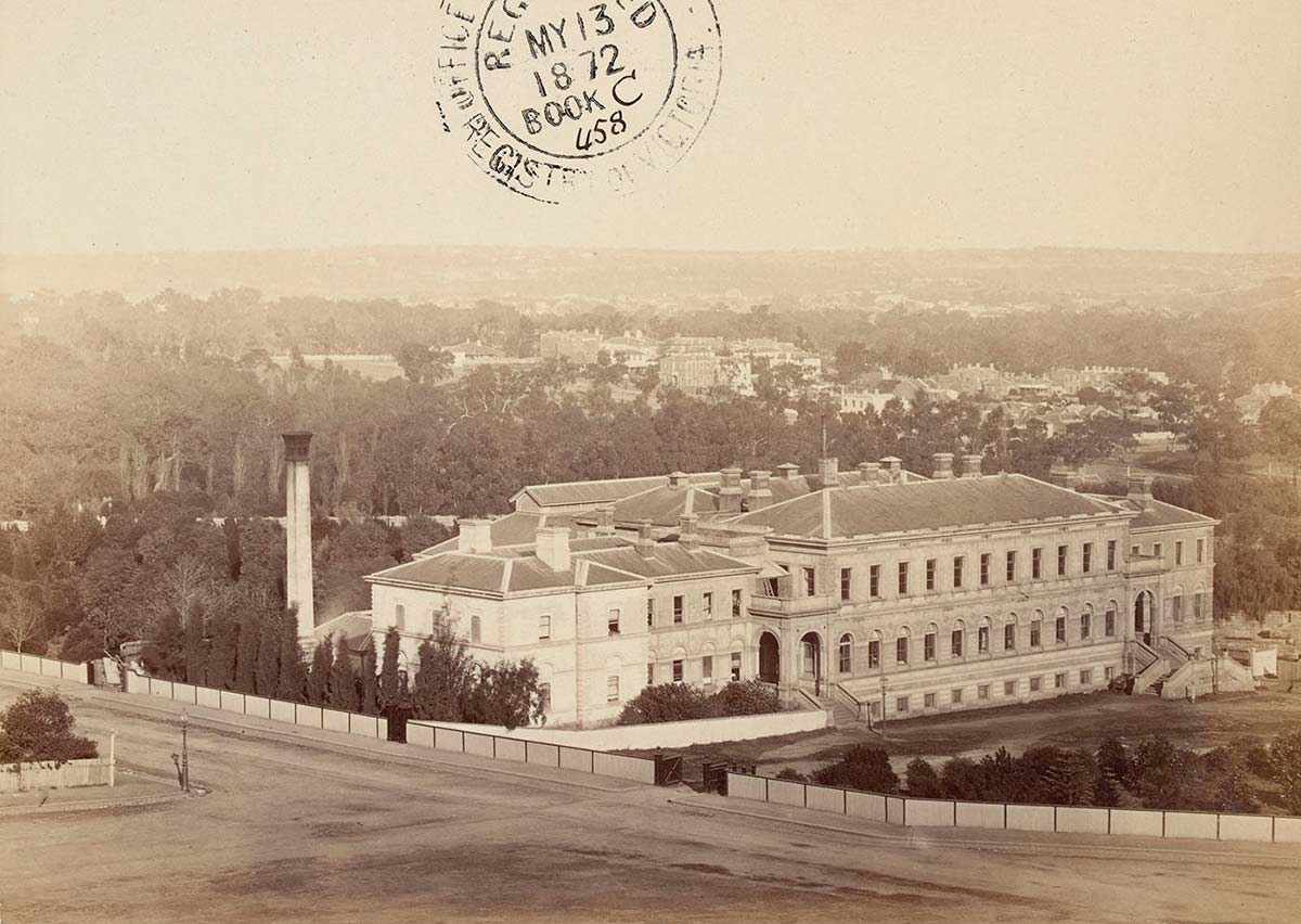 Sepia-toned photograph of a large three-storey white building.