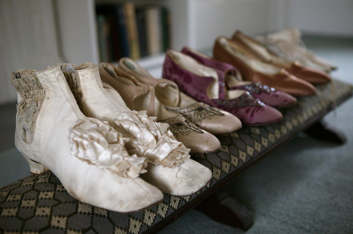 Colour photograph of five pairs of ladies shoes lined up on a low stool.