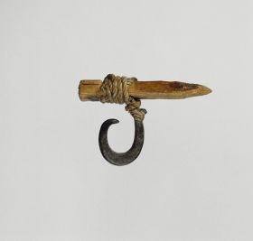 Fishhook matau Fishhook made of mother-of-pearl that is supported at the upper end of the shank where strings made of various plant fibres are attached and tied to a small piece of pale, light wood.