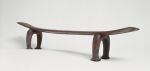Headrest kali Headrest made of wood, the ‘seat’ is slightly curved and supported by a pair of horseshoe-shaped legs. The ‘seat’ becomes wider from the middle towards both ends.