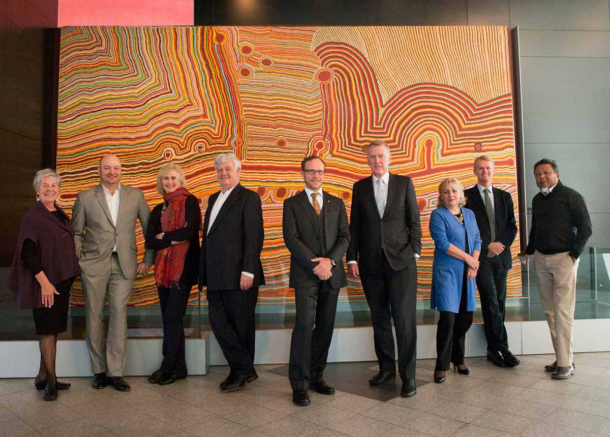 Council members standing in front of a large Aboriginal painting, from left: Barbara Piscitelli AM, Nicholas Davie, Andrea Hull AO, John Morse AM, Andrew Sayers AM, Daniel Gilbert AM, Rae Francis, David Jones, Peter Yu. 