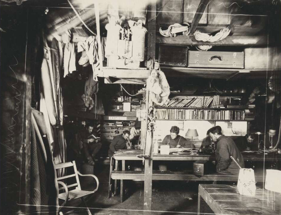 Black and white photograph of men inside hut.