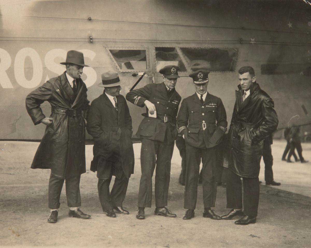 Photo of five men standing in front of an aeroplane.