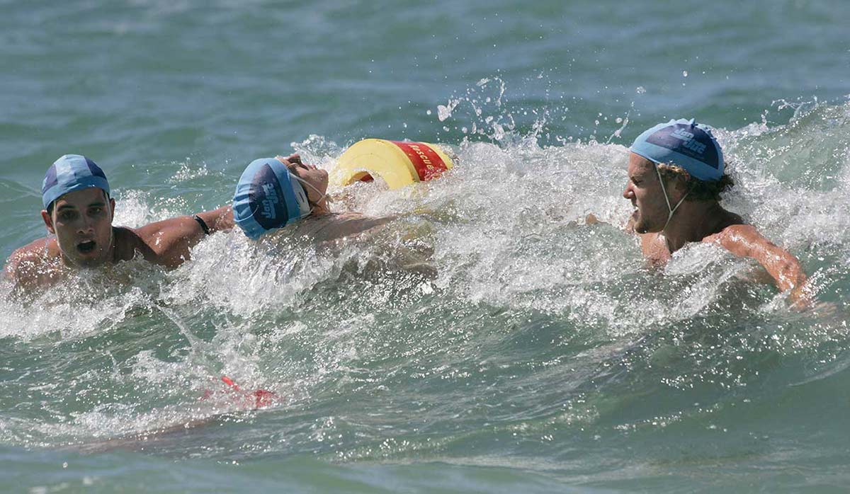 Surf lifesavers practising a rescue operation in the surf.