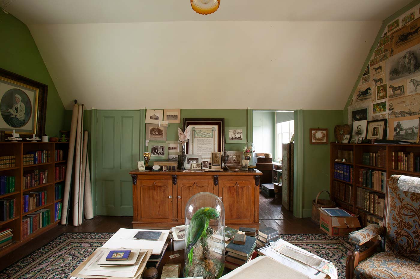 Interior view of a room filled with books, art, furniture and other various household objects.