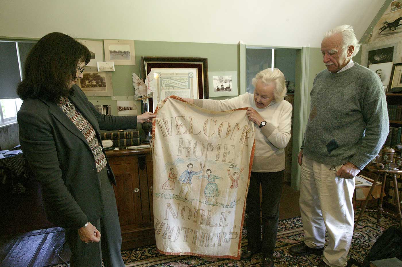 A colour photograph of Pamela and Jim Maple-Brown inside the Faithfull family museum with Carol Cooper from the National Museum of Australia.