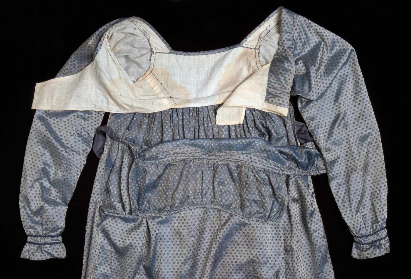 A view of the top of blue silk dress featuring the lowered shoulder straps.