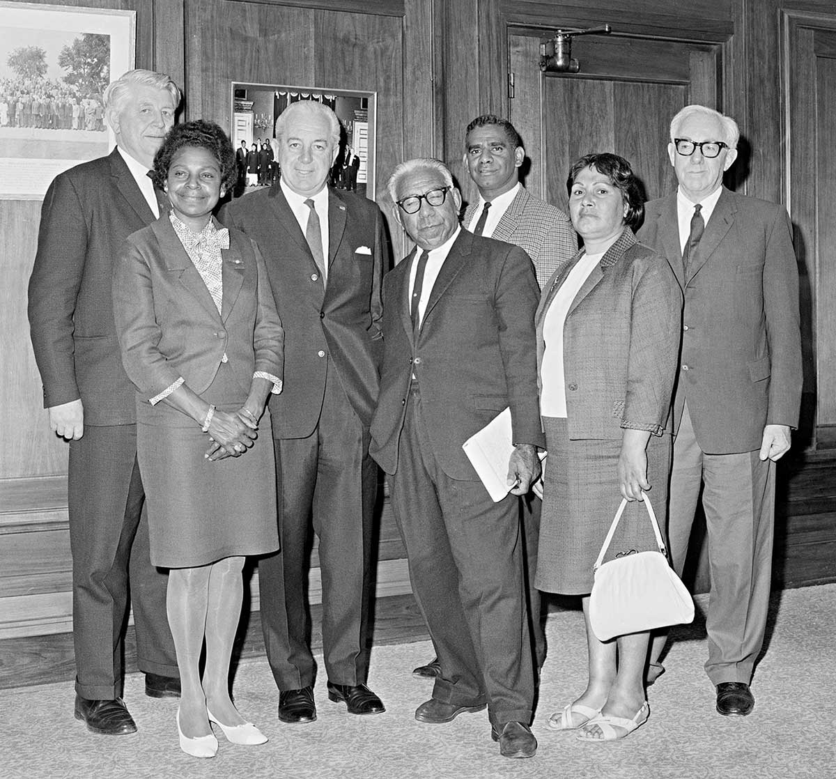Three politicians stand with four Aboriginal people in an office.
