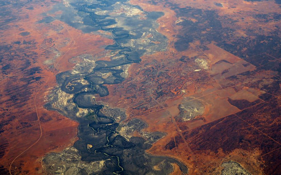 Colour photo of an aerial view of a dry riverbed running through arid landscape.