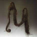 Bundle of hair Black human hair loosely and unevenly twisted into a long bundle, partly in loops.