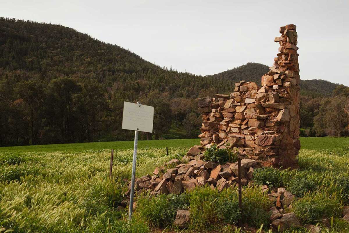 Remains of a stone building in a green field.