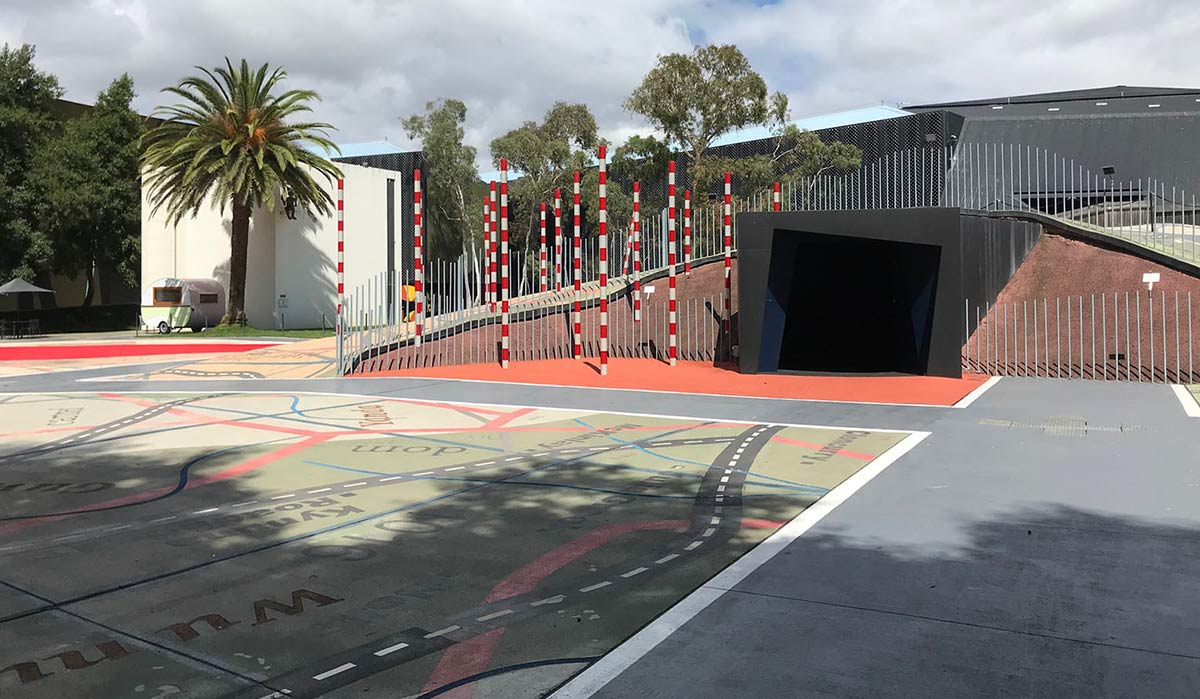 Enclosed outdoor space featuring a large map printed on the ground, palm trees and a mine shaft.