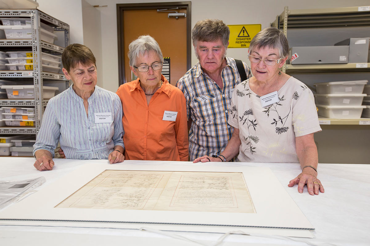 Four people standing behind a table with the letter of sympathy displayed in front of them.