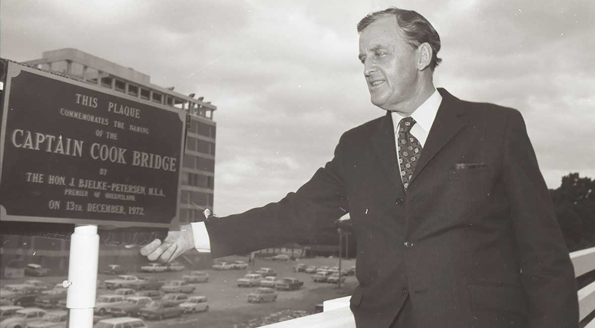 Man cutting ribbon on bridge across water.
