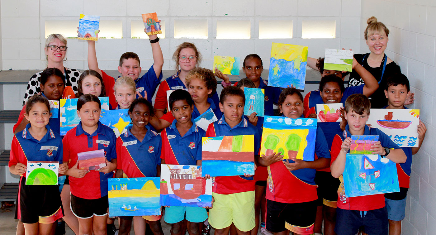 Group shot of primary school students and teachers display their finished paintings.