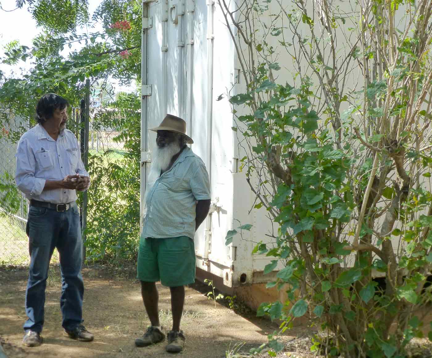 Photo of two men standing adjacent to a shipping container.