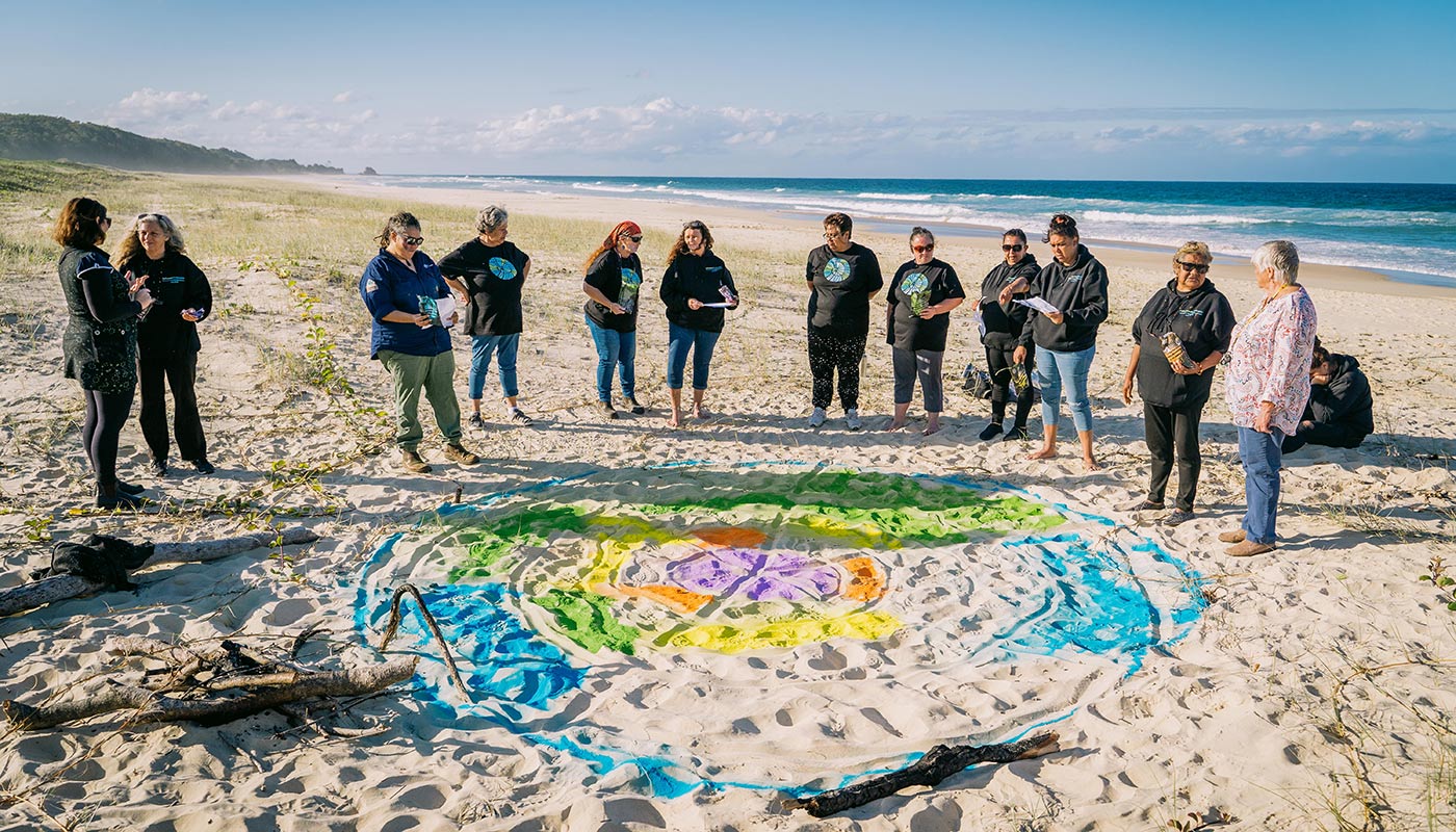 Women gathering together on a sandy beach.