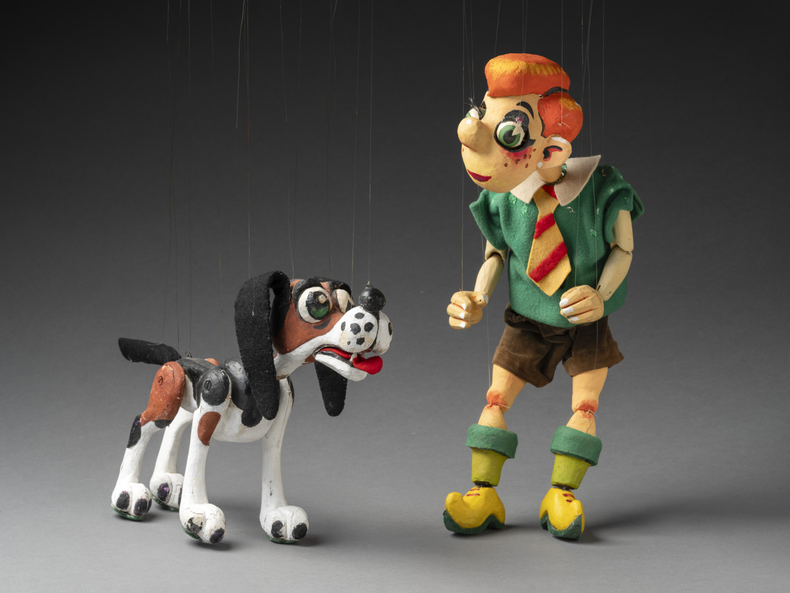 Photograph of characters Nicky and Noodle from Mr Squiggle. Nicky is a boy with red hair, green shirt and brown shorts. His dog noodle is brown, black and white with a bright red tongue.