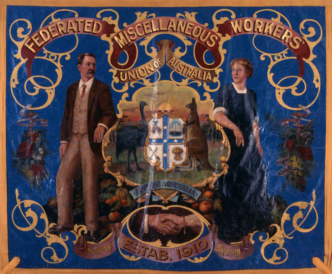 A painted banner with gold fabric border. The banner is painted royal blue with an image of a man and woman leaning on a central image of the coat of arms. 'FEDERATED MISCELLANEOUS WORKERS UNION OF AUSTRALIA' is painted in gold at teh top of the banner.