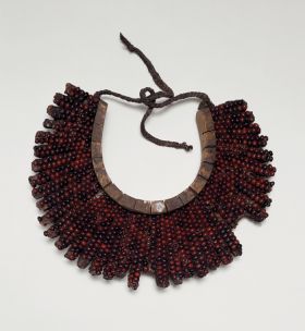 Breast ornament (gorget) Breast plate, formed into a crescent-shaped base made of light soft wood tied together. The breast is covered over with the beautiful red and black tropical peas.
