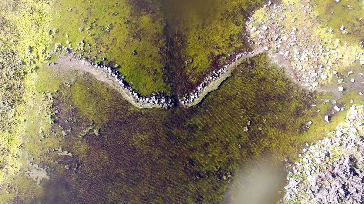 Aerial view of a landscape with a body water and basic looking walls fabricated from stone.