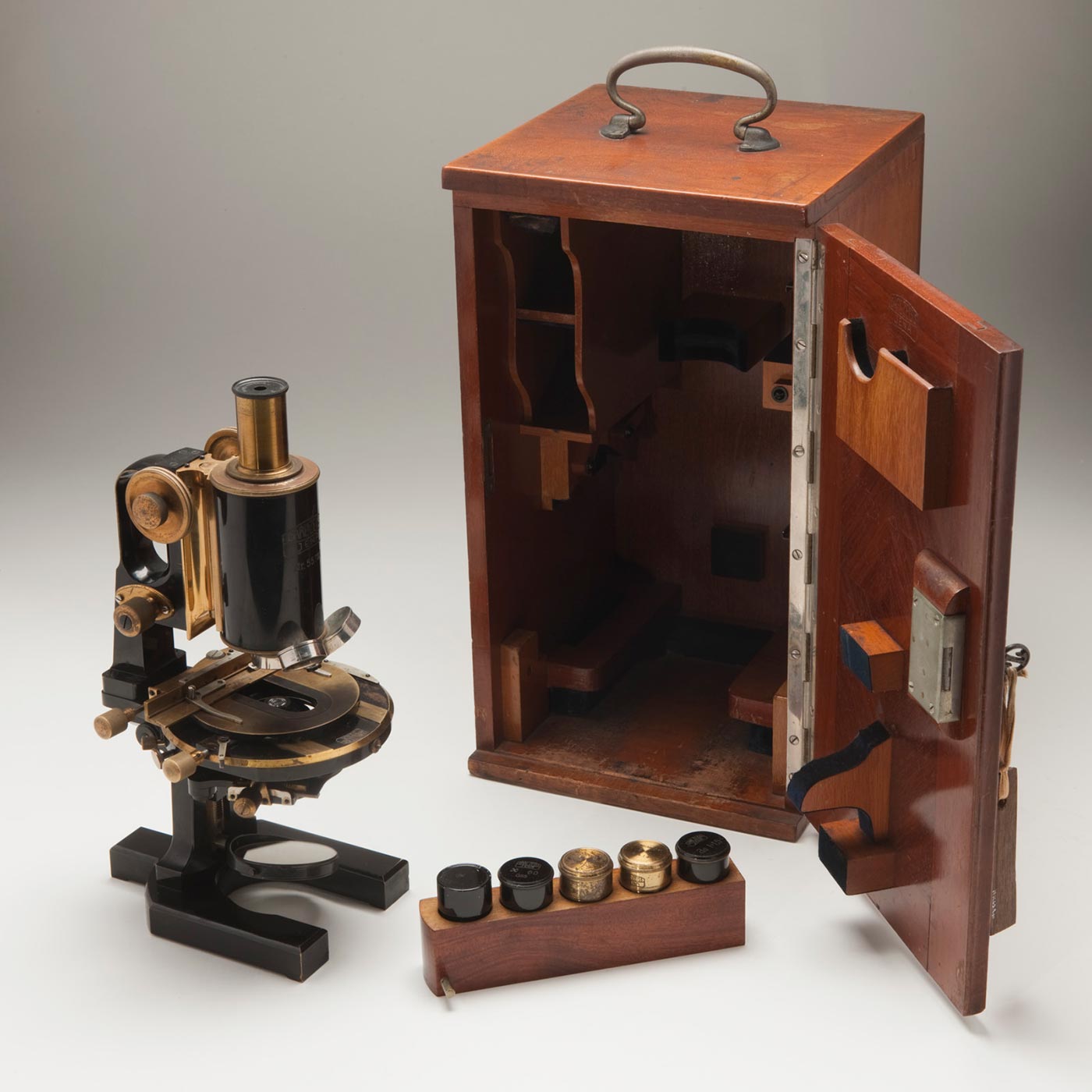 A small black telescope with brass fittings sits outside its wooden storage box.