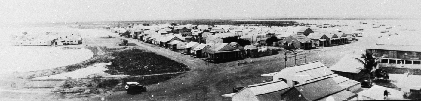 Black-and-white panorama photo of a rural township on a harbour.